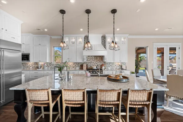 a kitchen with stainless steel appliances kitchen island granite countertop a dining table chairs and white cabinets