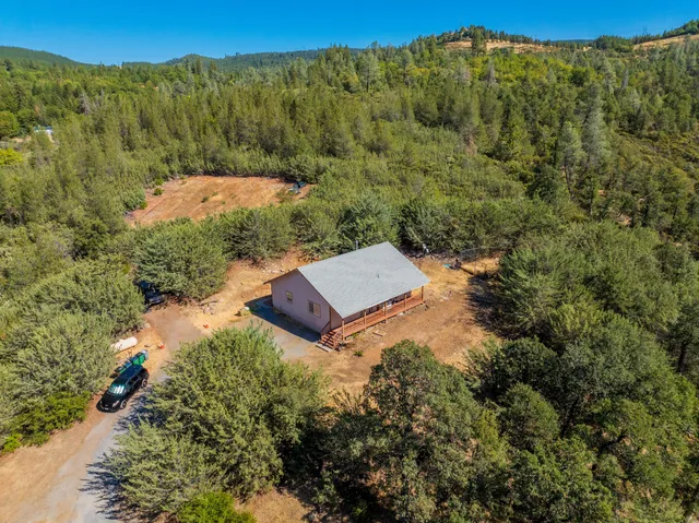 an aerial view of residential house with outdoor space and trees all around