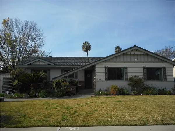 a front view of house with yard and trees in the background