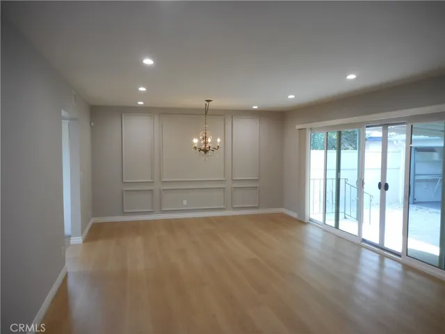 an empty room with a chandelier fan and windows