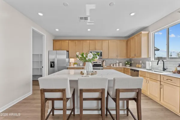 a kitchen with stainless steel appliances granite countertop a dining table chairs and white cabinets