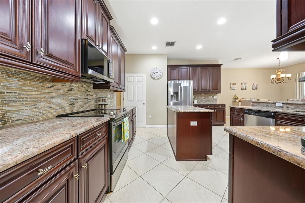 979 Counts Crest Circle Apopka, FL 32712 - Photo 14 of 48 a large kitchen with stainless steel appliances granite countertop wooden cabinets a sink and dishwasher a stove top oven with a dishwasher