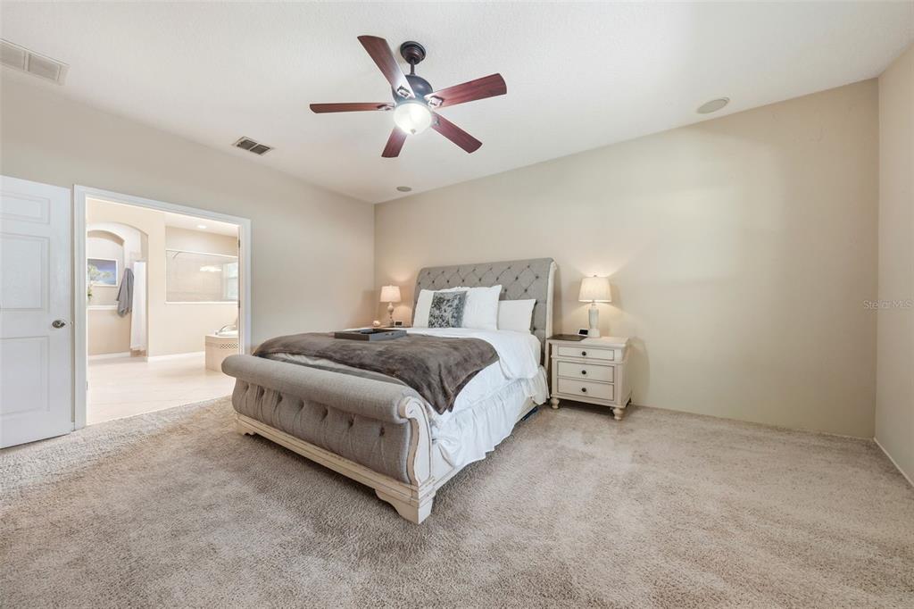979 Counts Crest Circle Apopka, FL 32712 - Photo 26 of 48 a spacious bedroom with a bed and a chandelier