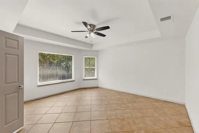a view of an empty room with a window and chandelier fan