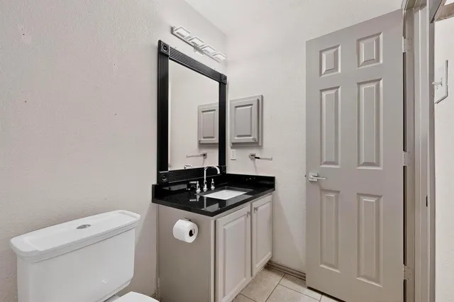 a bathroom with a granite countertop sink and a toilet