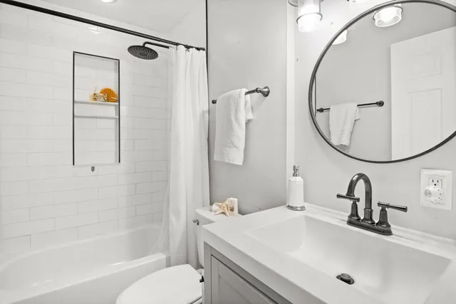a bathroom with a sink and mirror with bathtub
