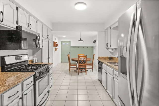 a kitchen with granite countertop a refrigerator stove top oven and sink
