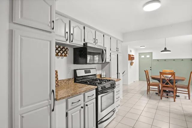 a kitchen with stainless steel appliances a stove a sink cabinets and a dining table