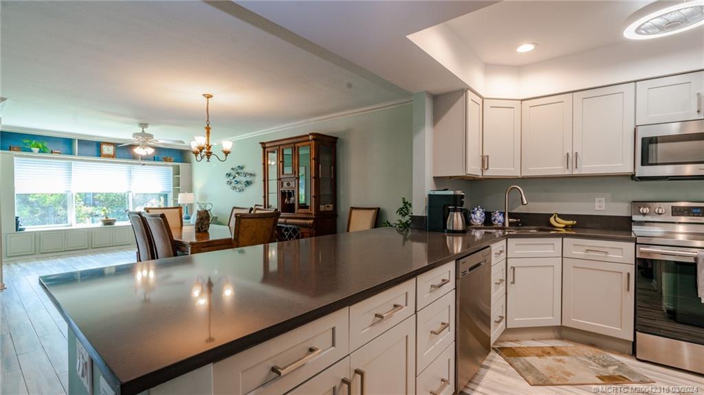 a kitchen with stainless steel appliances granite countertop a sink a stove white cabinets with dining table and chairs