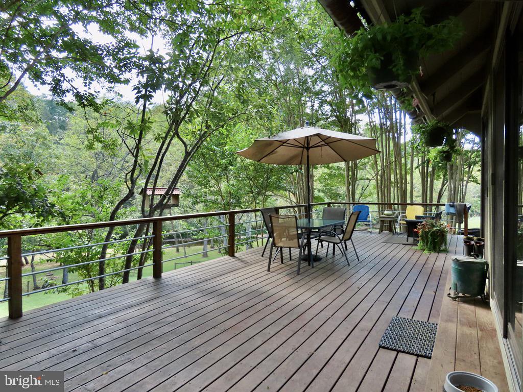180 5 Forks Road Woodville, VA 22749 - Photo 6 of 44 a view of a roof deck with table and chairs under an umbrella with wooden floor