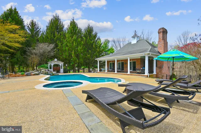 an aerial view of a swimming pool with outdoor seating and yard