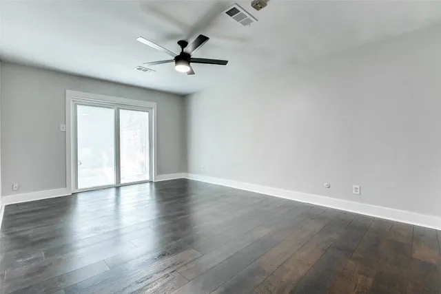 an empty room with wooden floor and ceiling fan