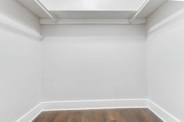 an empty room with wooden floor ceiling fan and windows