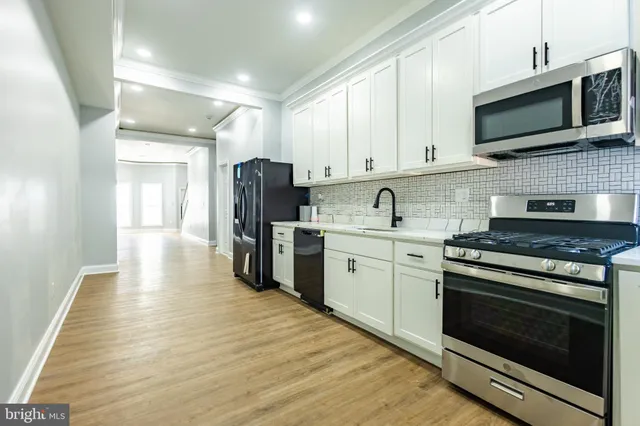 a kitchen with stainless steel appliances granite countertop a stove top oven a refrigerator a sink and dishwasher with wooden floor