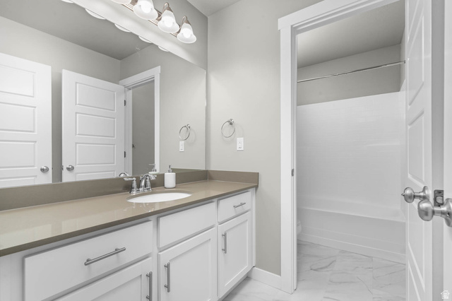 5686 Duke Lane Tooele, UT 84074 - Photo 15 of 38 Bathroom featuring vanity, bathtub / shower combination, and light marble finish floors