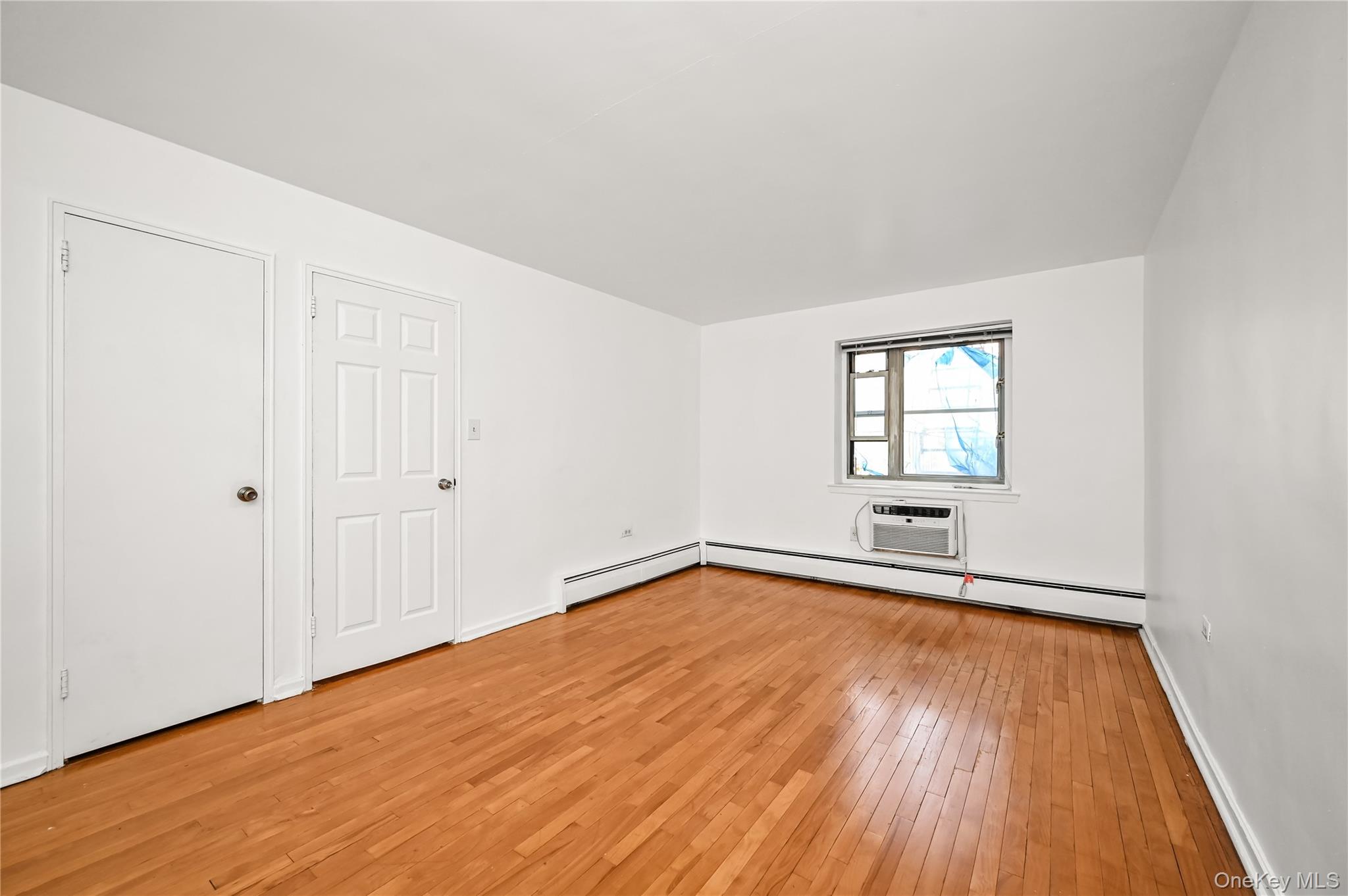 99-10 60th Avenue, Unit 3B Queens, NY 11368 - Photo 13 of 25 an empty room with wooden floor and windows