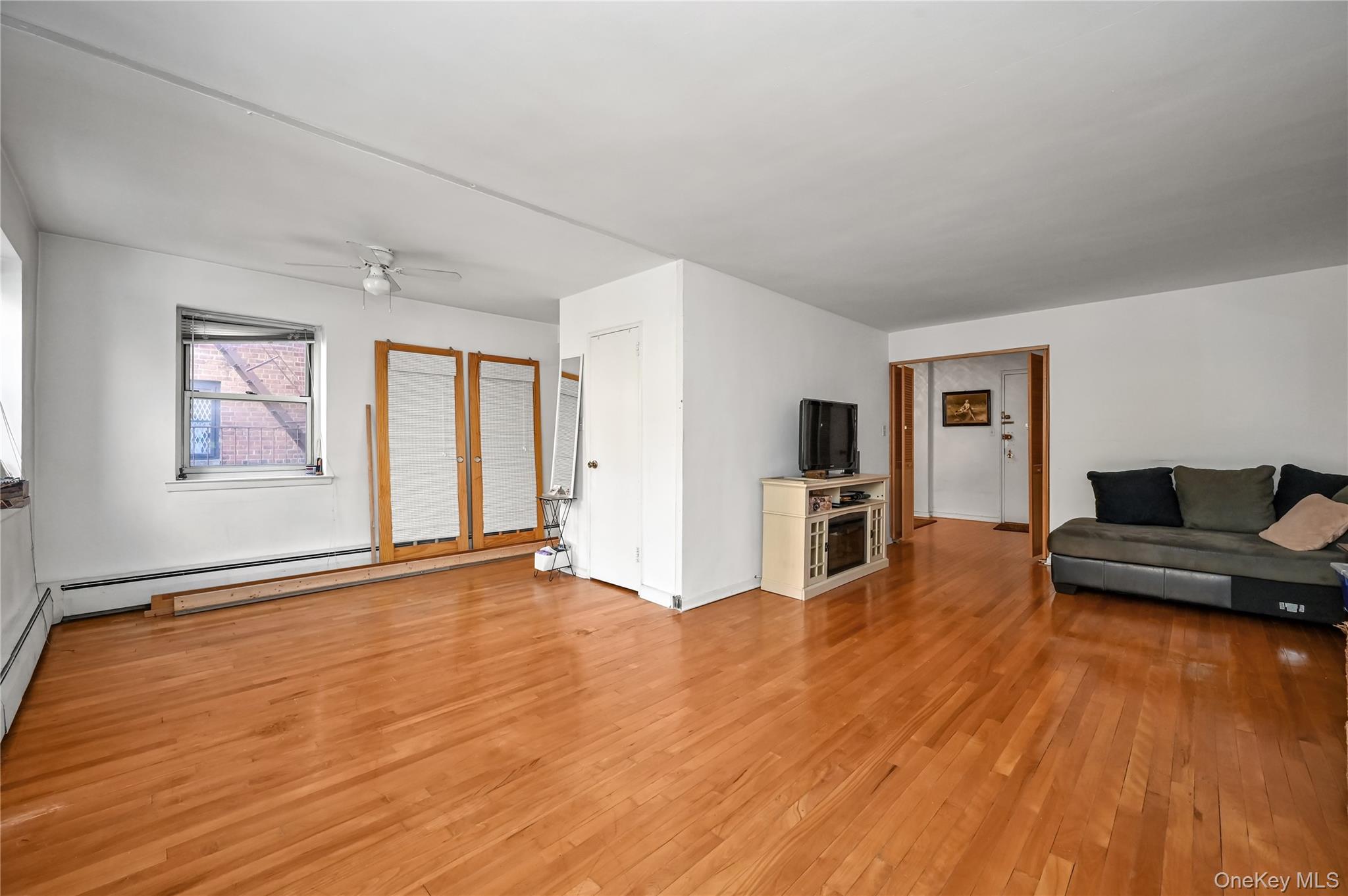 99-10 60th Avenue, Unit 3B Queens, NY 11368 - Photo 8 of 25 a view of empty room with wooden floor and fireplace