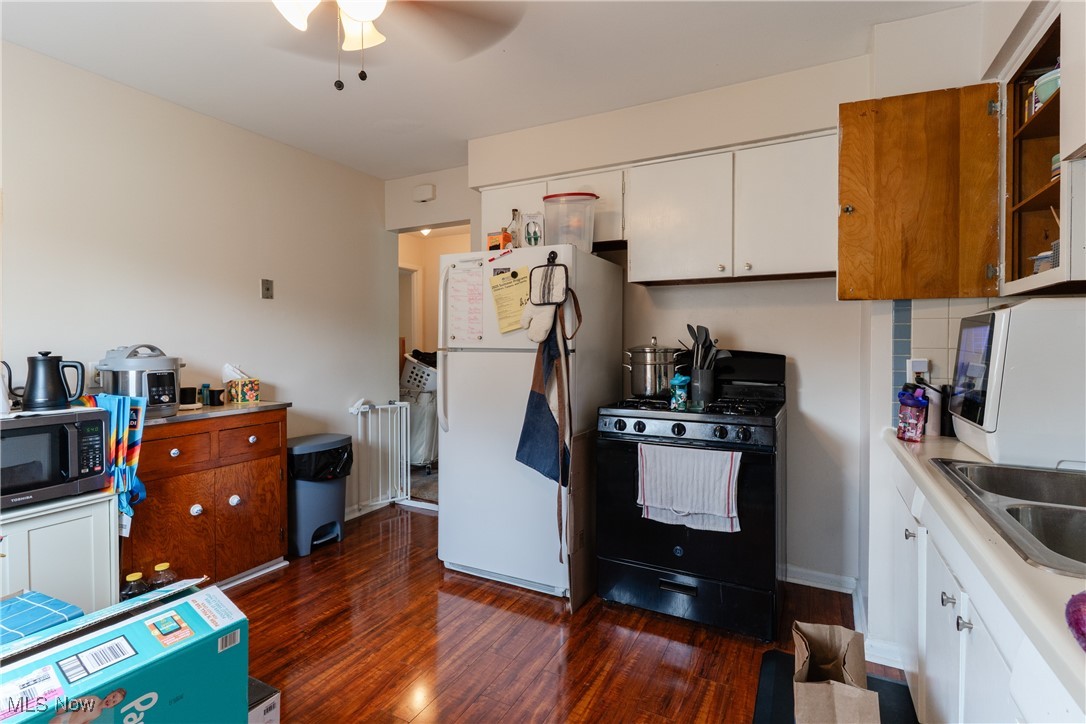 14220 Triskett Road Cleveland, OH 44111 - Photo 24 of 32 Kitchen featuring black range with gas stovetop, freestanding refrigerator, a ceiling fan, dark wood-style flooring, and a sink