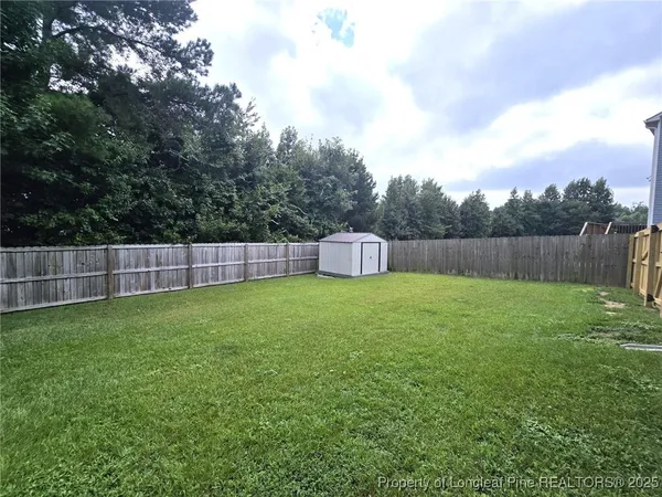 a view of yard with swimming pool and wooden fence