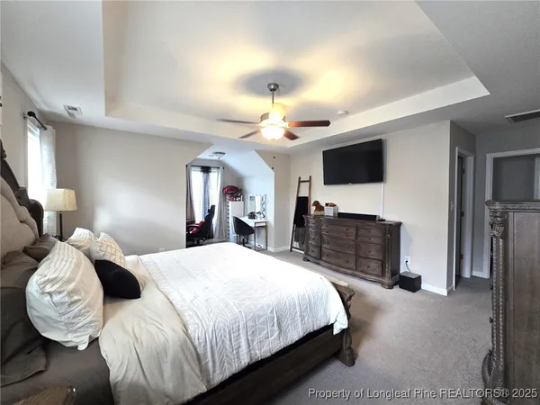 a bedroom with a large bed and a flat tv screen on dresser