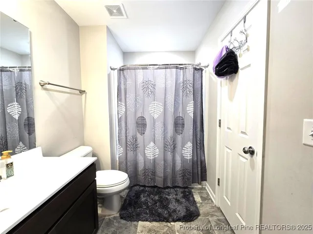 a bathroom with a granite countertop sink a toilet a shower and a mirror