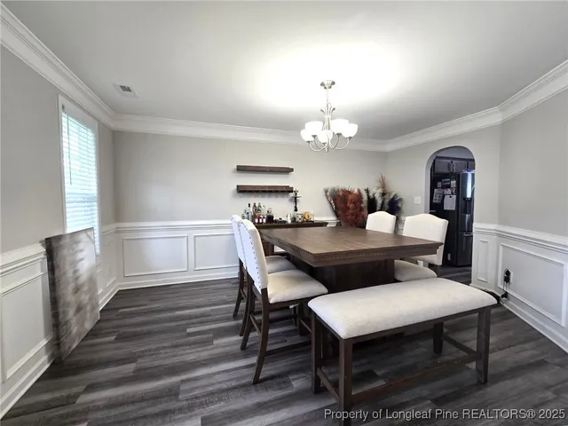 a dining room with furniture a chandelier and wooden floor