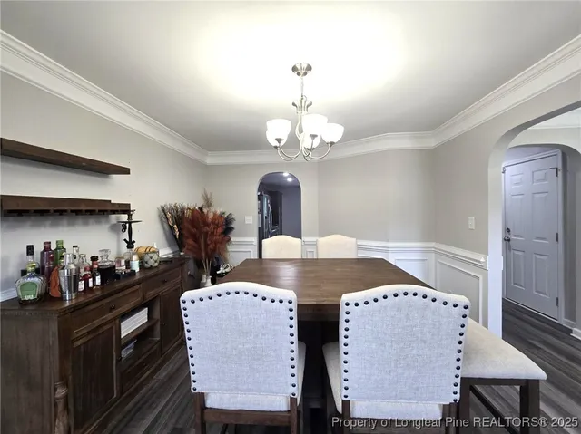 a dining room with wooden floor a chandelier a wooden table and chairs