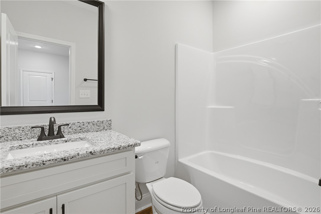 1523 McBryde Lake Road Raeford, NC 28376 - Photo 22 of 32 a bathroom with a granite countertop toilet a sink and a bathtub