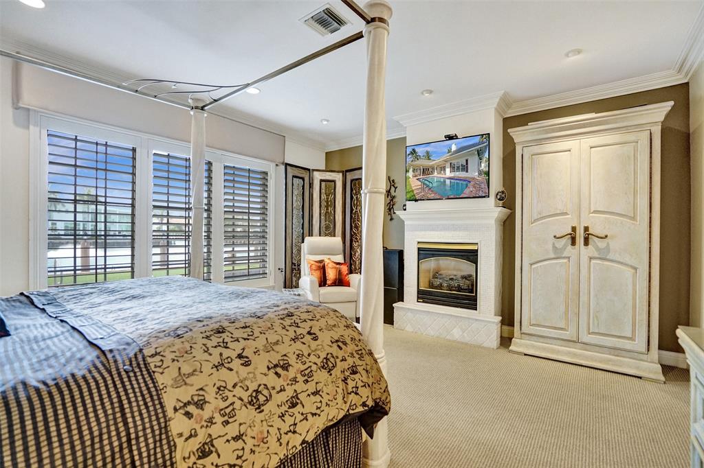 7 Saranac Road Sea Ranch Lakes, FL 33308 - Photo 45 of 93 a spacious bedroom with a balcony a bed and a fireplace