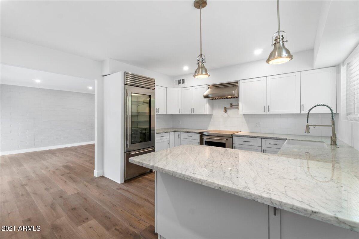4041 East Camelback Road, Unit 2 Phoenix, AZ 85018 - Photo 9 of 25 a kitchen with stainless steel appliances granite countertop a sink a microwave a refrigerator and wooden floors