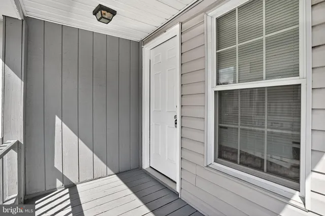 a view of an empty room with wooden floor and windows