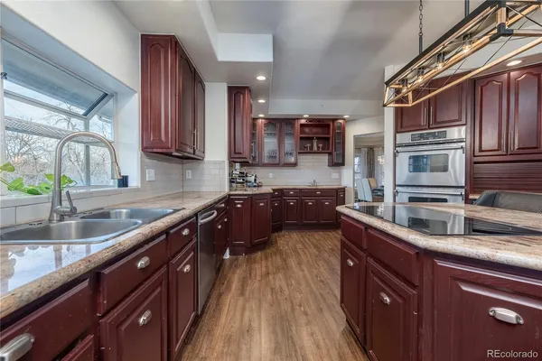 a kitchen with stainless steel appliances granite countertop a sink a stove and a wooden cabinets