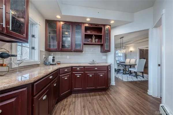 a kitchen with stainless steel appliances granite countertop wooden cabinets a sink dishwasher a stove and a refrigerator with wooden floor