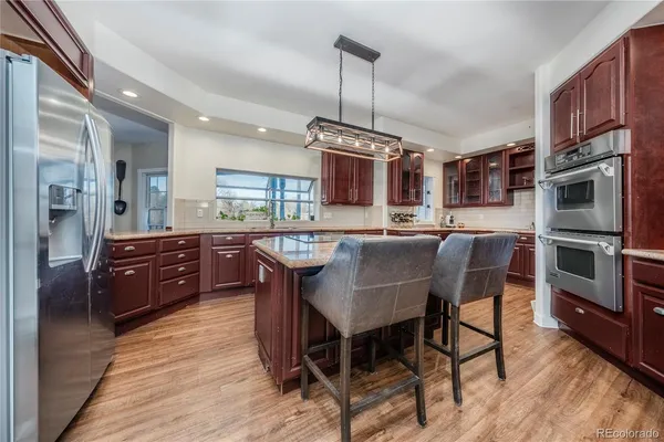 a kitchen with stainless steel appliances granite countertop a sink a stove a refrigerator cabinets a dining table and chairs