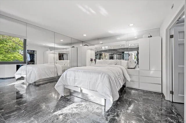 a spacious bedroom with a bed a couch and a large window