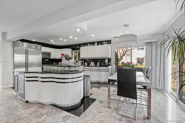 a kitchen with kitchen island stainless steel appliances a sink a stove a refrigerator and chairs