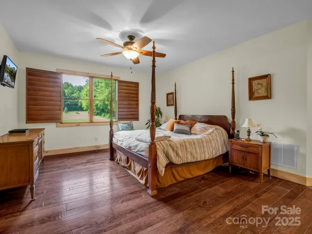 a bedroom with a bed ceiling fan and a wooden floor