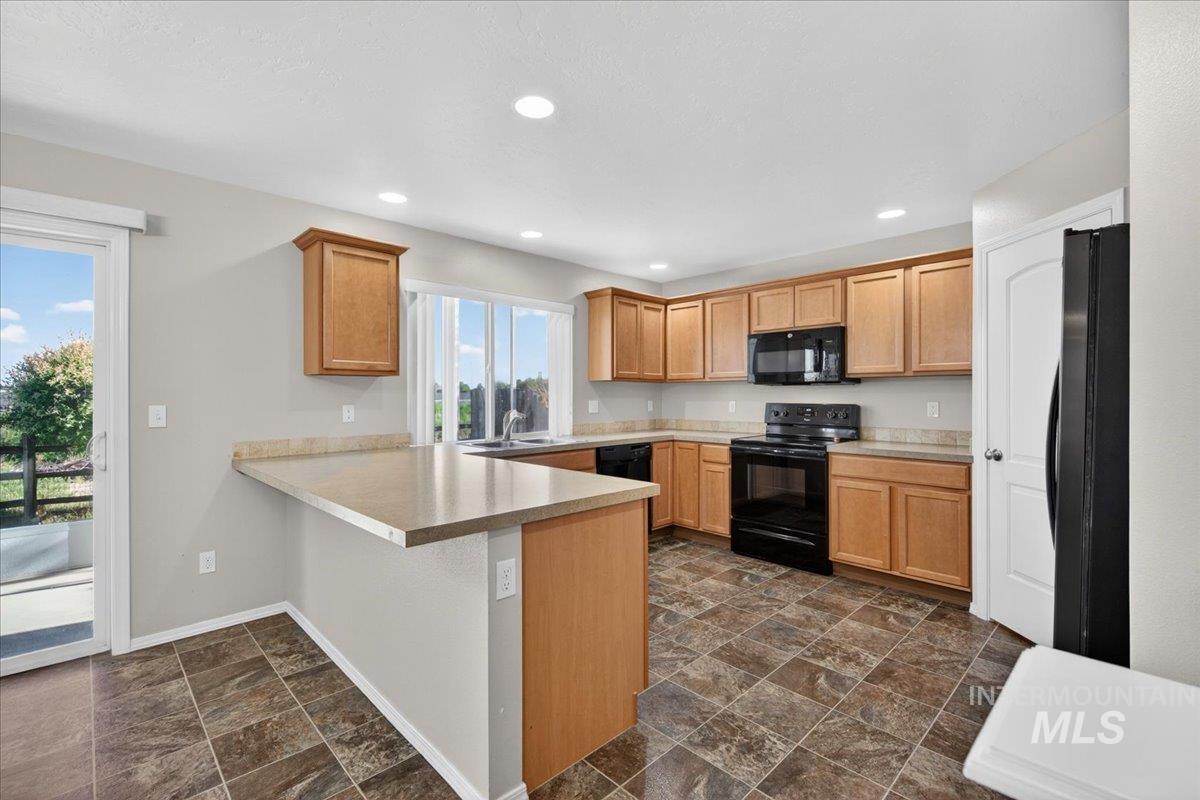 1555 Condor Drive Middleton, ID 83644 - Photo 6 of 50 Kitchen featuring wood cabinetry, black appliances, tile flooring, recessed lighting, and a sliding glass door