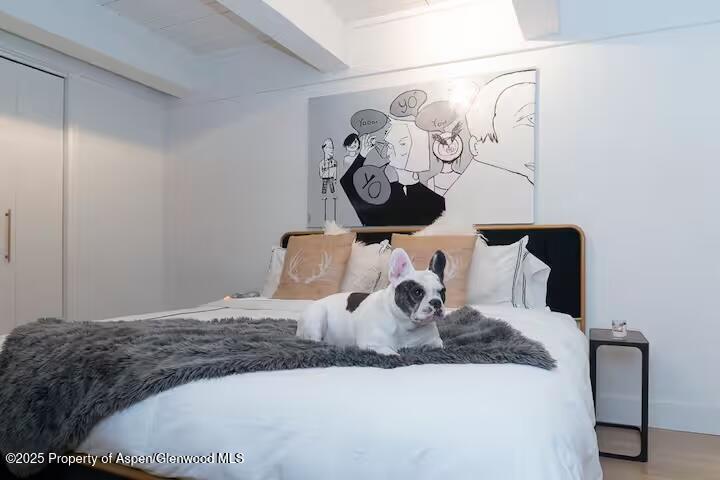 1039 East Cooper Avenue, Unit 16A Aspen, CO 81611 - Photo 19 of 37 a bedroom with a large bed and a chandelier