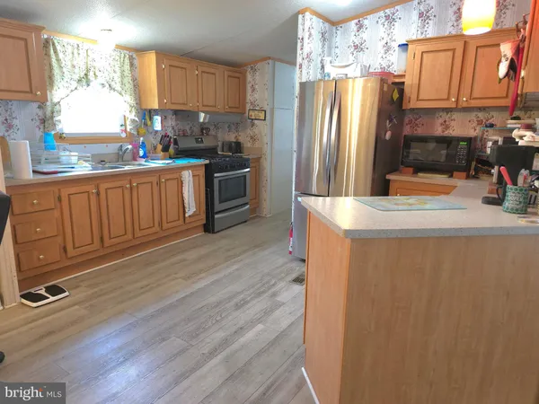 a kitchen with stainless steel appliances granite countertop a refrigerator a stove and a sink with wooden floors