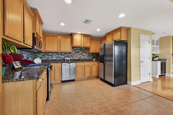a kitchen with stainless steel appliances granite countertop a refrigerator a stove and a sink