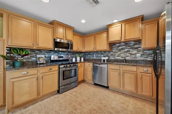 a kitchen with granite countertop a sink stainless steel appliances and cabinets