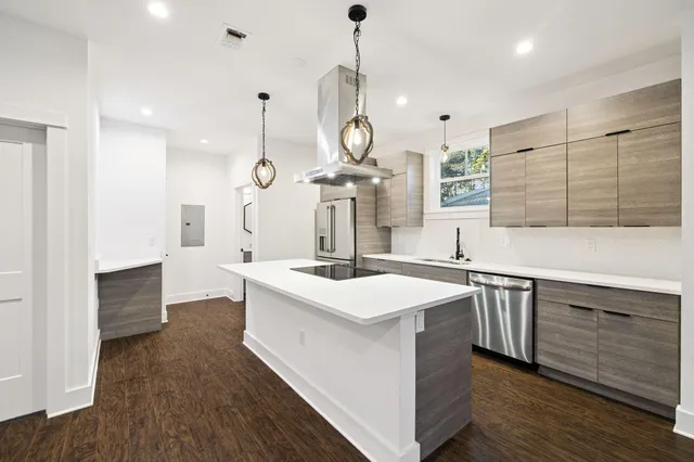 a kitchen with stainless steel appliances granite countertop a refrigerator a sink dishwasher a oven with white cabinets and wooden floor