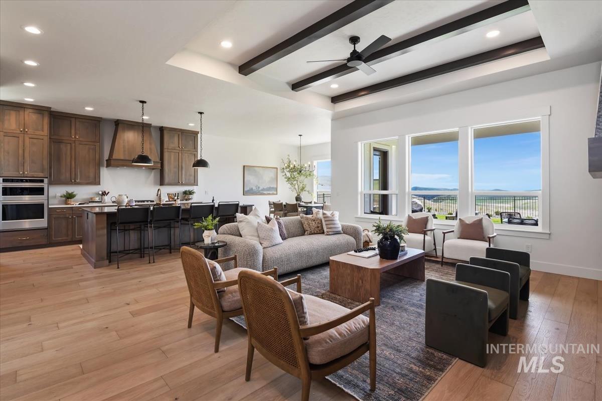 7615 Brown Way Eagle, ID 83714 - Photo 10 of 43 Open concept living space featuring wood-finish flooring, a kitchen island with seating, integrated wall ovens, and a coffered ceiling with exposed beams