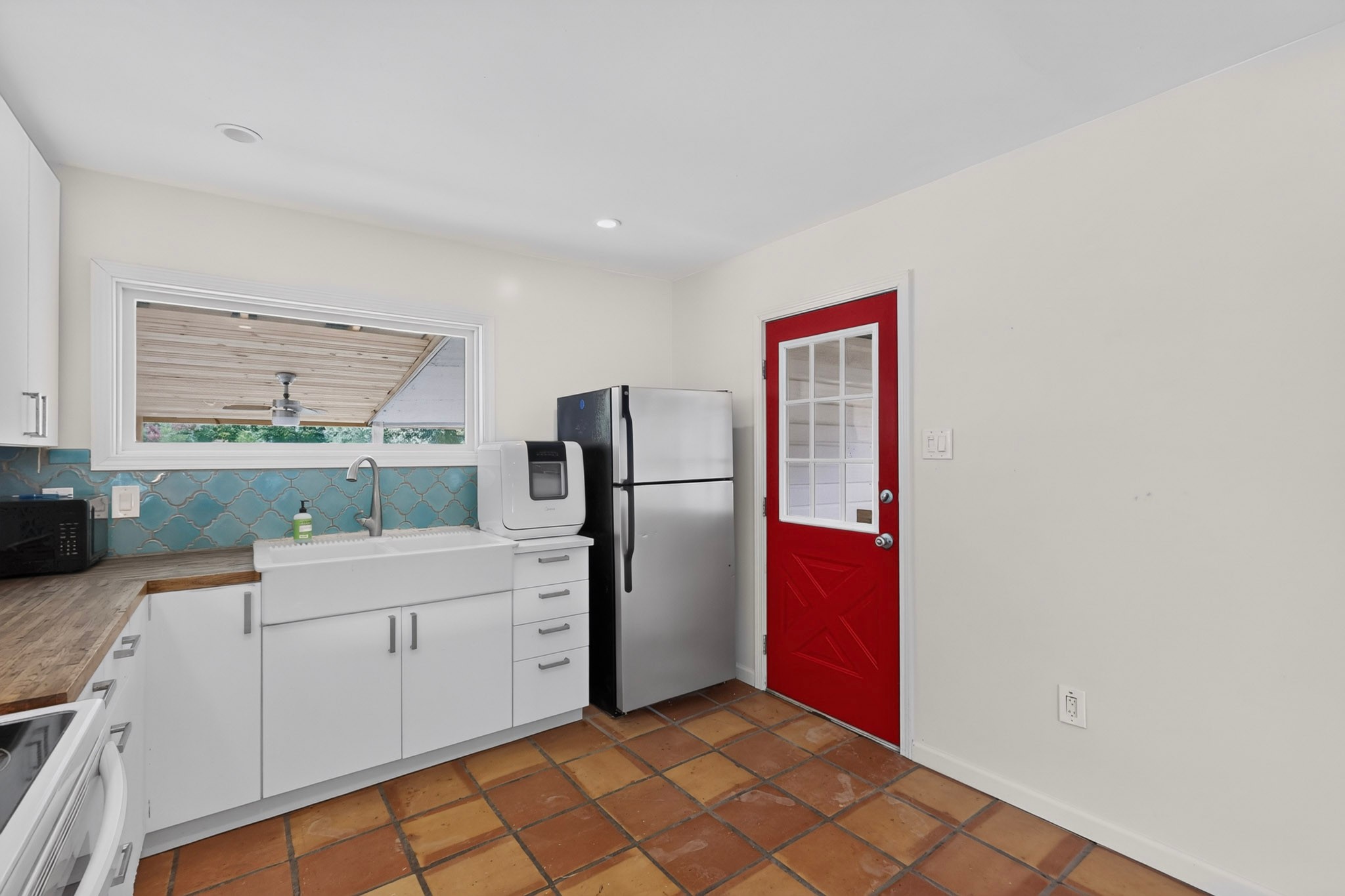 4711 Alf Avenue Austin, TX 78721 - Photo 12 of 34 A well-lit kitchen featuring tiled floors and a charming red entry door.