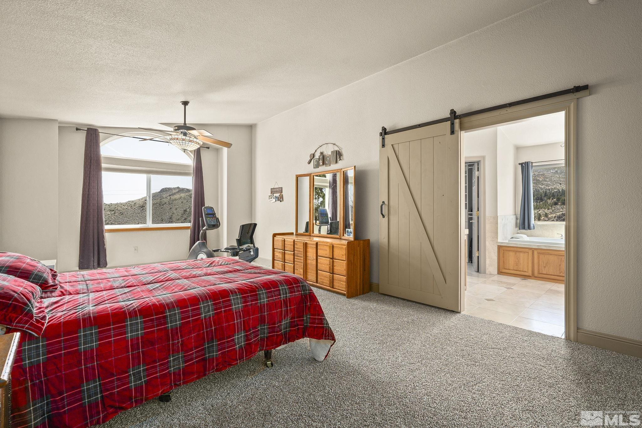 480 Duck Hill Road Washoe Valley, NV 89704 - Photo 19 of 46 a bedroom with a bed a table and large window