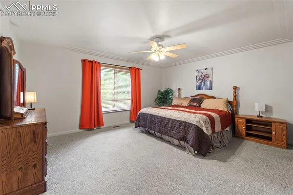 a spacious bedroom with a bed a dresser and a large window