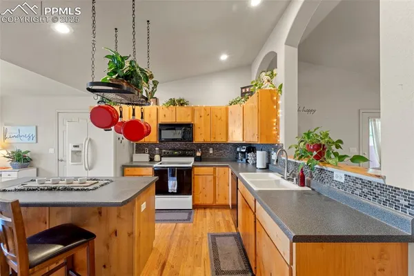 a kitchen with stainless steel appliances granite countertop a sink a stove and a wooden floors