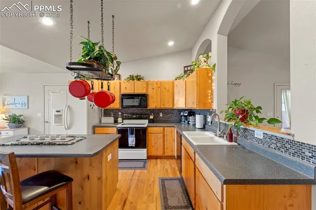a kitchen with stainless steel appliances granite countertop a sink a stove and a wooden floors