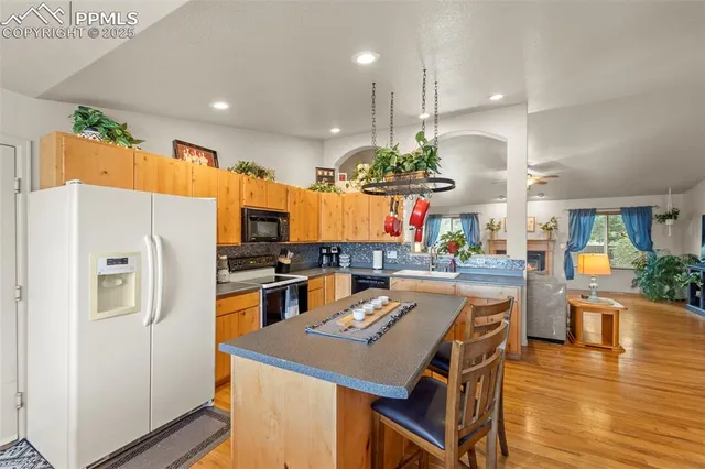 a kitchen with a refrigerator a stove and a dining table with wooden floor